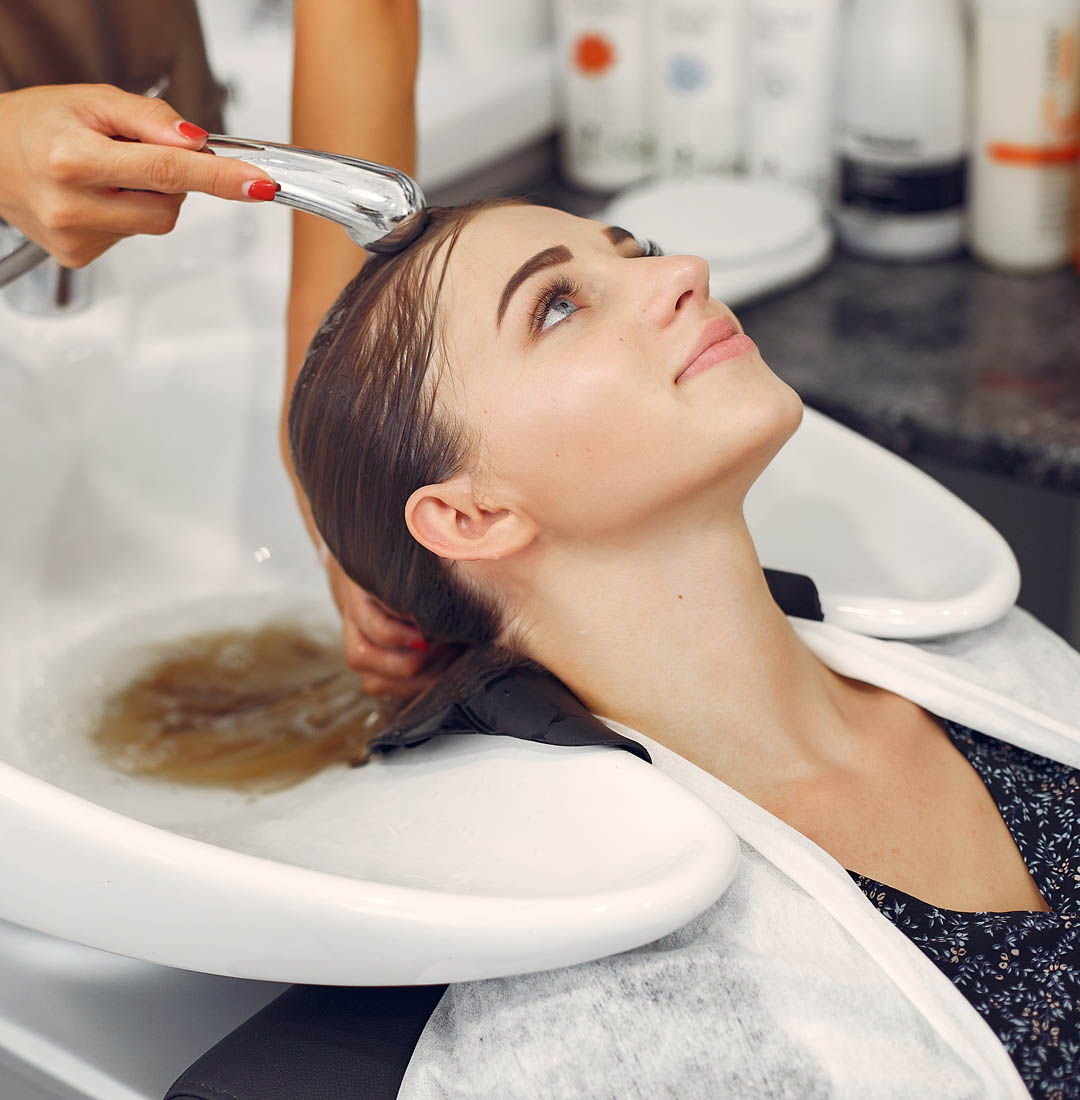 Hairdresser washing head her client. Woman in a hair salon